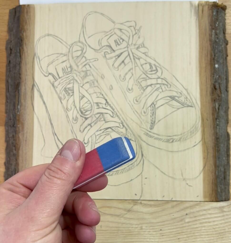 Erasing the dark lines to leave lighter lines for wood burning.