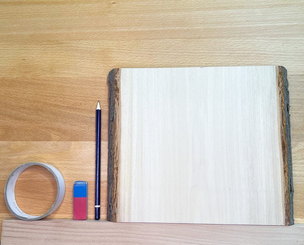Tools for transferring a picture to wood Tape, eraser, pencil, and live edge wooden board.
